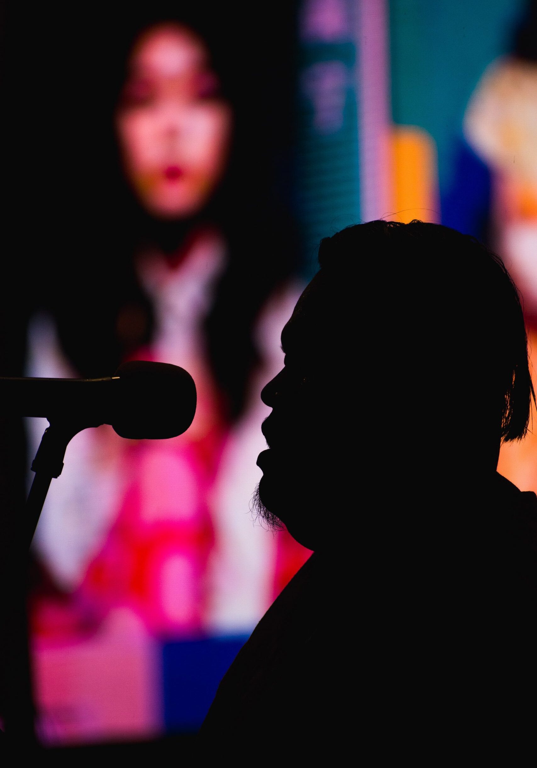 silhouette photography of man in front of a microphone